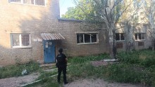 Правоохоронець стоїть на фоні пошкодженої адміністративної будівлі.