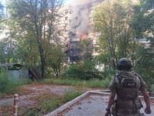 Пожежа в будинку, який пошкодили окупанти та правоохоронець, який стоїть поруч