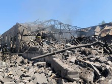 Господарська будівля, знищена ворогом та пожежник зі шлангом, який гасить займання вогню посеред руїн.