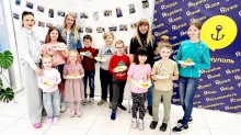 Діти та дорослі фотографуються біля банера зі своїми поробками