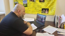 Начальник управління з питань ветеранської політики Донецької облдержадміністрації Артур Насібян бере участь у відеозустрічі з представниками громад та родинами загиблих Захисників і Захисниць України. На екрані — учасники онлайн-наради, де обговорювали питання підтримки ветеранів і родин полеглих.