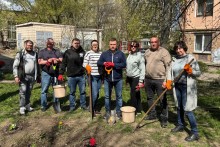 Учасники акції стоять з садовим інвентарем та висаджують квіти.