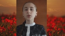 Учасниця фестивалю читає вірш на фоні зображення макового поля