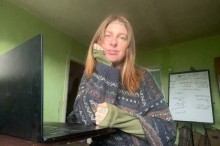 Бойова медикиня з позивним «Гайка» сидить перед ноутбуком у кімнаті