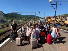 Діти з валізами на пероні залізничного вокзалу, чекають на потяг.