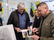 Заступник начальника Бахмутської міської військової адміністрації Олександр Марченко та Урбан Фрай роздивляються фотокартки міста Бахмут.