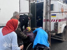 Люди похилого віку, в тому числі маломобільні, та рятувальник групи "Фенікс" здійснюють посадку на евакуацію