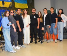 Спільне фото учасників проєкту «Молодь у дії: шлях до активної громади». Хлопці та дівчата посміхаються. На задньому плані прапори України та Донеччини.