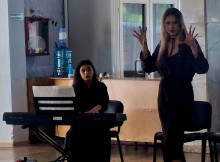 Акторка розводить руками під акомпанемент синтезатора