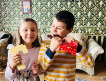 Хлопчик куштує велику шоколадку, дівчинка поруч тримає у руках солодощі.