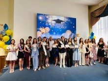 Групове фото випускників Бахмутської громади з нагородами під час урочистої церемонії у святково прикрашеній залі; на екрані позаду напис «Вітаємо!».