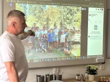 Начальник Сіверської міської військової адміністрації Олексій Воробйов стоїть біля екрана, показує фото дітей та розповідає про них.