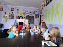 Діти сидять за столом, фахівець Центру розповідає про державні символи та орнаменти, демонструючи зображення