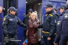 Рятувальники зустрічають евакуйовану жінку з потяга