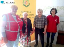 Спільне фото. Представниці Червоного хреста та чоловік з жінкою похилого віку.