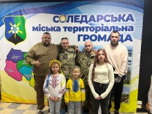 Захисники Соледарської територіальної громади,  представник Соледарської громади, діти Соледарської територіальної громади фотографуються на фоні банеру громади