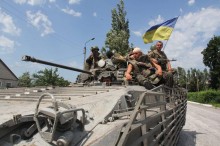 Солдати Збройних сил України, які брали участь у операції звільнення Сіверська у 2014 р. Сидять зверху на танку, поруч майорить прапор України.