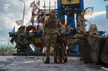 Поліцейський з службовою собакою біля стели Донецької області.