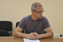 Учасник наради, сидить за столом та уважно слухає.