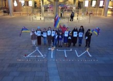 Учасники акції тримають прапори України та партнерів біля напису на асфальті Діти