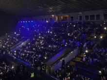 Глядачі у залі на благодійному концерті «Тримаємо світло», святять ліхтариками.