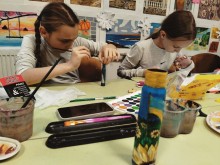 Солотвинська громада організувала майстер-клас з розпису гільз. Дівчата сидять за партою та майструють.