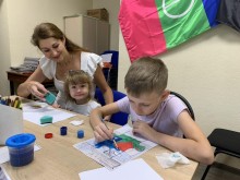 Маленькі діти разом із педагогом займаються малюванням, створюючи яскраві малюнки, атмосфера тепла та турботи.