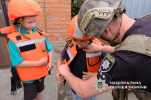 Поліцейський допомагає дітям вдягнути бронежилети