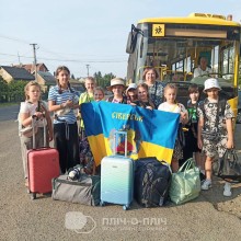 Група дітей біля автобусу з прапором громади