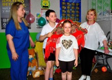 Хлопчик та дівчинка під наглядом ведучих приймають участь у конкурсі, хлопчик надягає дівчинці хустку