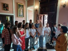 Учні Краматорського ВПУ стоять у просторій залі з високими стелями та великими дерев'яними дверима. Стіни прикрашені картинами у старовинних рамах.