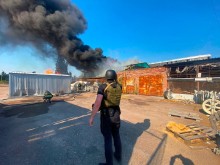 Правоохоронець і пожежник стоять біля пошкоджених ворожим обстрілом господарських будівель