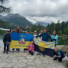 Діти Сіверської громади на фоні гір та озера, попереду тримають прапори громади та Донеччини.