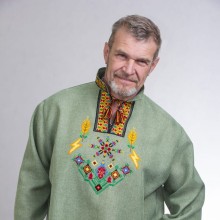 Чоловік одягнений у лляну вишиванку оливкового кольору із геометричними та рослинними мотивами