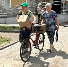 Жінки на велосипеді везуть коробки з гуманітарною допомогою