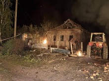 Зруйнована та обгоріла будівля та трактор, який допомагає розбирати завали.