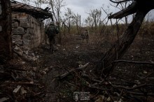 Двоє піхотинців з зеленими смужками на рукавах, обережно проходять скрізь розбиту будівлю та понівечені дерева.