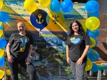 Освітяни на фоні синьо-жовтого банеру "Я-Маріуполь" з повітряним кульками.