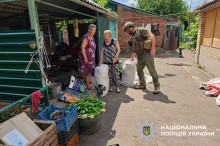 Поліцейський допомогає літнім жінкам зібрати речі першої необхідності для евакуації