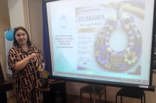 Ведуча заходу тримає декоративну підкову біля екрана з презентацією майстер-класу «Підкова на щастя!»