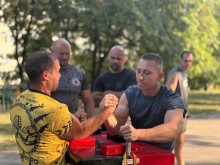 Турнір з армрестлінгу, двоє спортсменів змагаються. Поруч чоловіки, які спостерігають.
