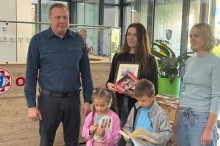 Олександр Шевченко та двоє дітей із розгорнутими книжками позирують у холі лікарні