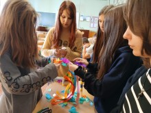 П'ятеро дівчат, які займаються виготовленням патріотичних сувенірів. У руках кожної - кольорові стрічки.