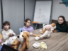 Група дітей Бахмутської громади на занятті Хібукі-терапії, оточені м’якими песиками-обіймаками, які допомагають їм відновити спокій і довіру до світу