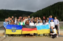 Група учнів тримає прапори України та Німеччини, символізуючи дружбу й співпрацю між країнами.
