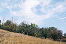 Український військовий посеред посадки. У повній екіпіровці йде оглядати територію. Над ним блакитне небо України.