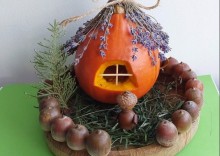 Мініатюрний будиночок з гарбуза з дахом із лаванди, оточений жолудями та травою на дерев'яній підставці