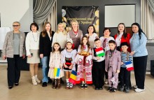 Спільне фото. Представники громад та дітей. Дівчина у національному вбранні тримає на рушнику паляницю.