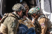 Парамедики розміщують лежачу літню жінку в спецтранспорті для евакуації