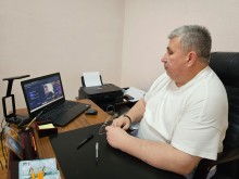 Представник військової адміністрації сидить за столом та слухає доповідача на семінарі